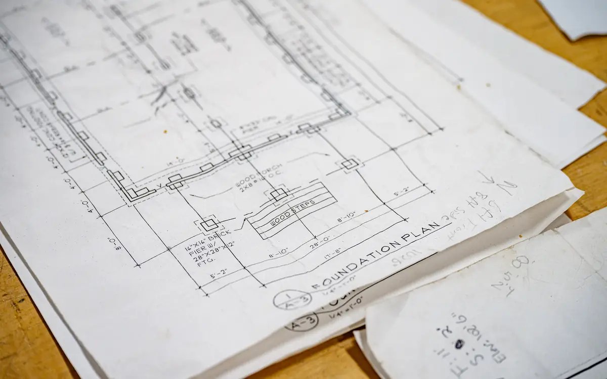 Printed foundation plan drawings spread across a wooden table