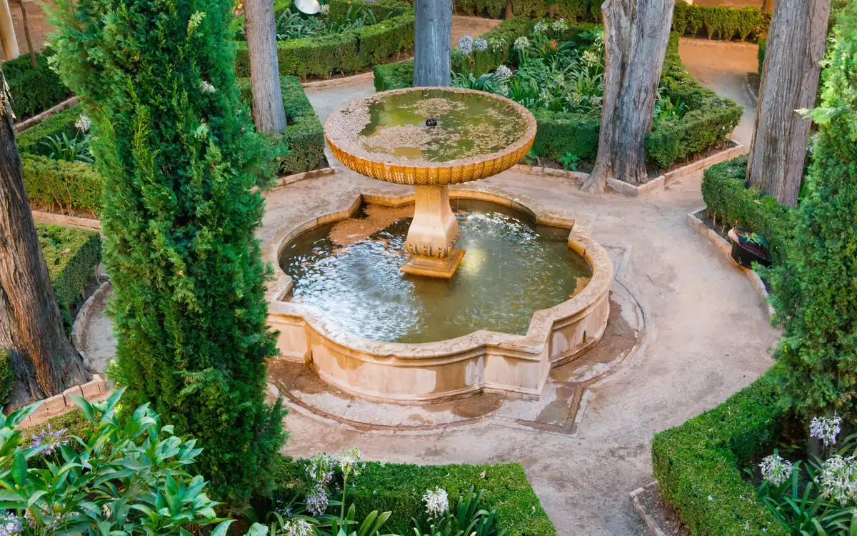 Stone fountain in a courtyard garden with clipped hedges and gravel paths